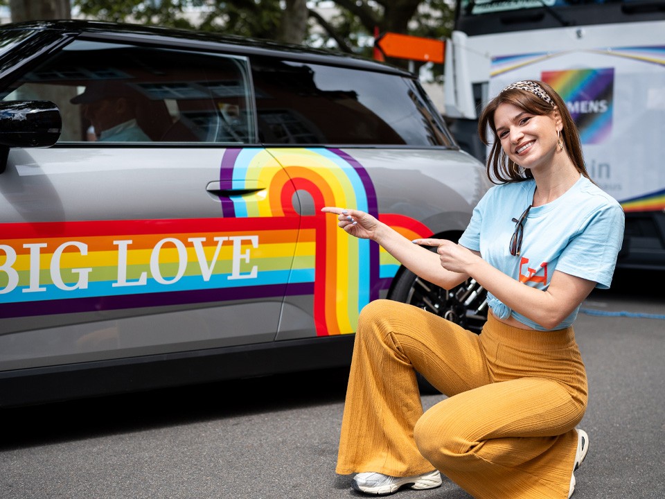 Détail MINI avec arc-en-ciel et inscription Big Love, femme accroupie Détail MINI arc-en-ciel et inscription Big Love, femme accroupie